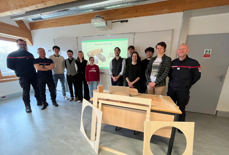 Un groupe d’étudiants de l’ESB et de sapeurs-pompiers pose ensemble dans une salle de cours devant la présentation du projet de parcours TASSS.