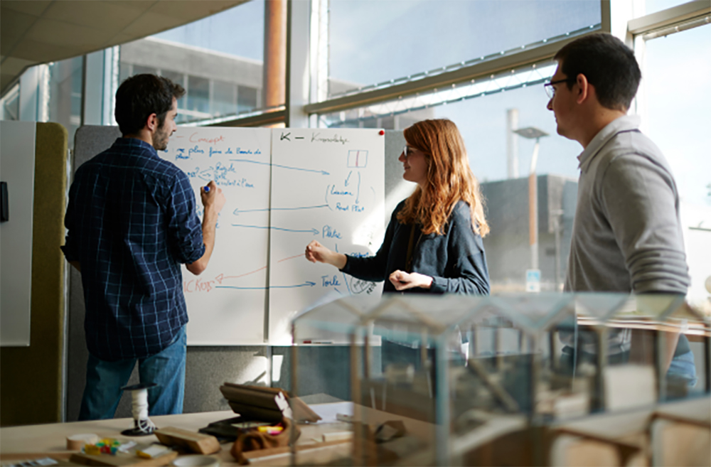 Deux étudiants et leur enseignant travaillent devant un tableau blanc à l’École Supérieure du Bois (ESB).