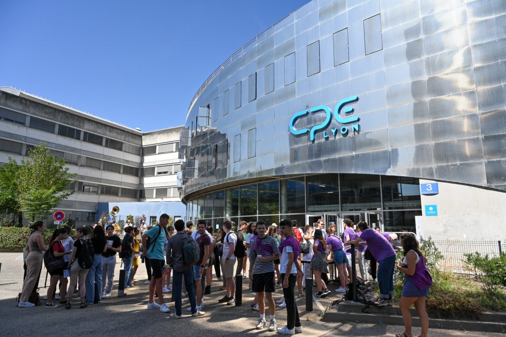 Groupe d'étudiants rassemblés devant l'entrée moderne du bâtiment CPE Lyon par une journée ensoleillée.