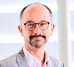 Portrait en plan rapproché d'Alexandre Moulin, Directeur de CPE Lyon, souriant, portant des lunettes et un costume gris sur une chemise claire.